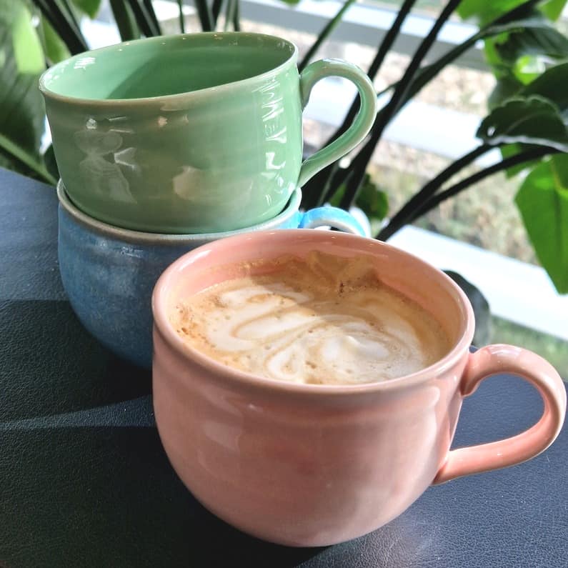 pastelfarvet kop med hank lyserød med cafe latte i